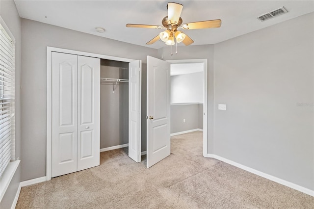 unfurnished bedroom with light carpet, a closet, and ceiling fan