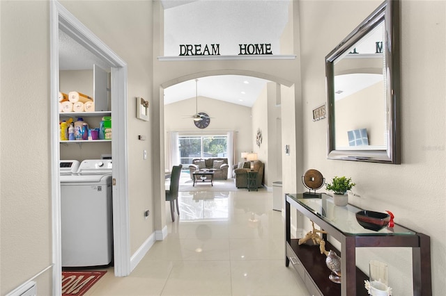 hallway featuring washing machine and dryer, lofted ceiling, and light tile patterned flooring