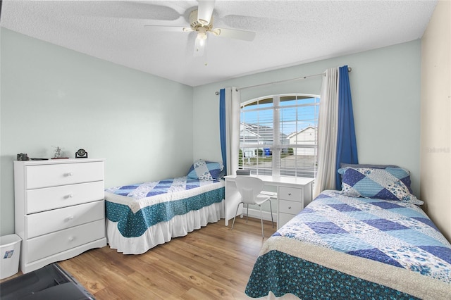 bedroom featuring ceiling fan, light hardwood / wood-style floors, and a textured ceiling