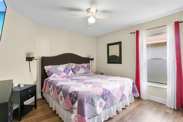 bedroom featuring ceiling fan, light hardwood / wood-style floors, and a textured ceiling