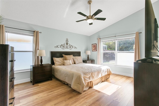 bedroom featuring stainless steel fridge, light wood-type flooring, baseboard heating, ceiling fan, and lofted ceiling