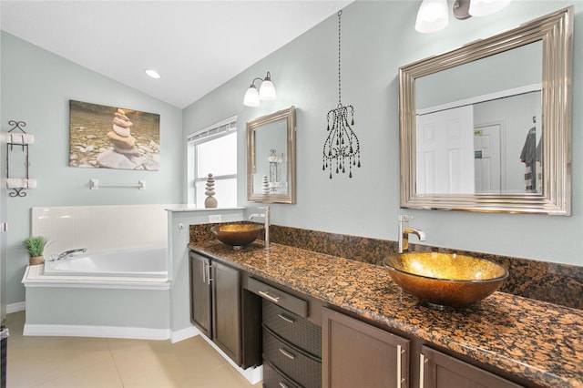 bathroom with a washtub, vanity, vaulted ceiling, and tile patterned flooring