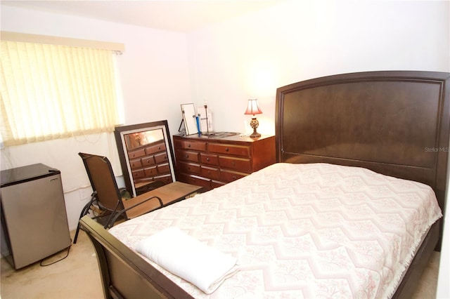 carpeted bedroom with stainless steel refrigerator