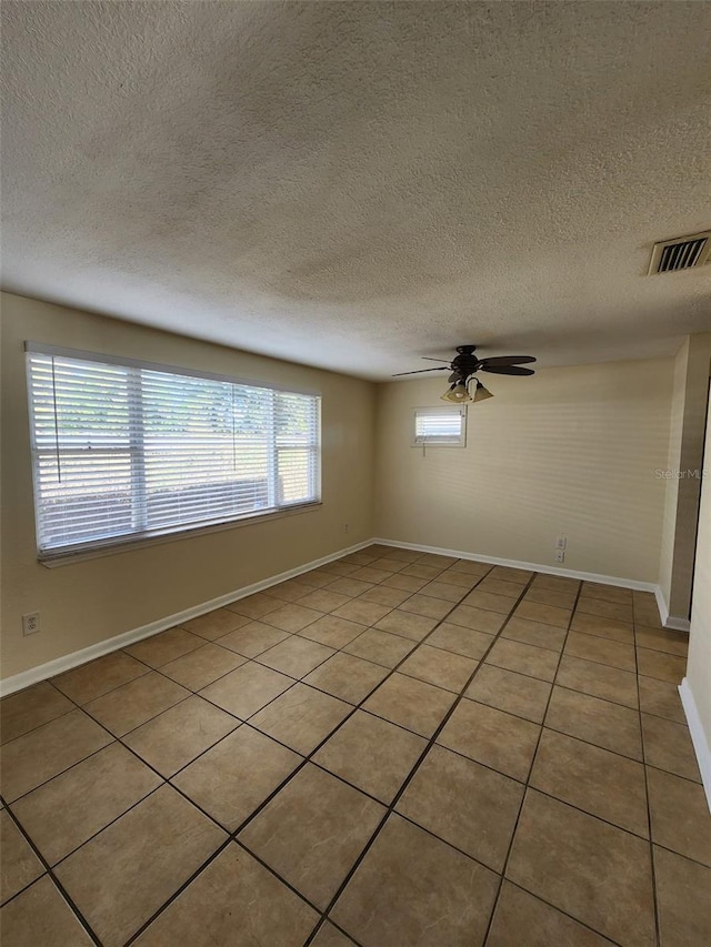 empty room with a textured ceiling, ceiling fan, and light tile patterned flooring