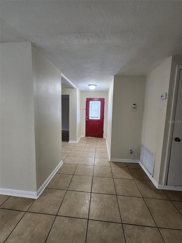 hallway featuring light tile patterned floors and a textured ceiling