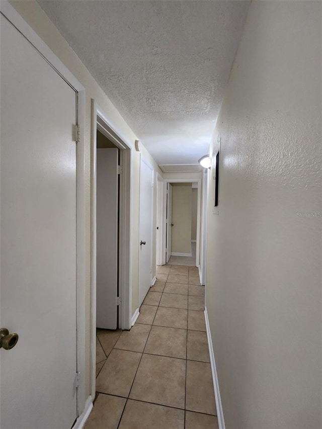 hall featuring light tile patterned flooring and a textured ceiling