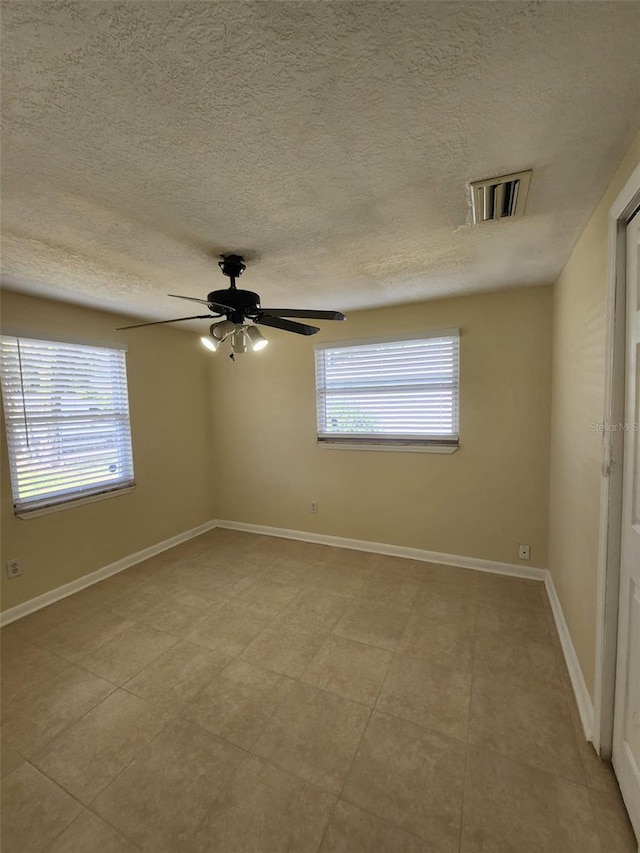 empty room with ceiling fan and a textured ceiling