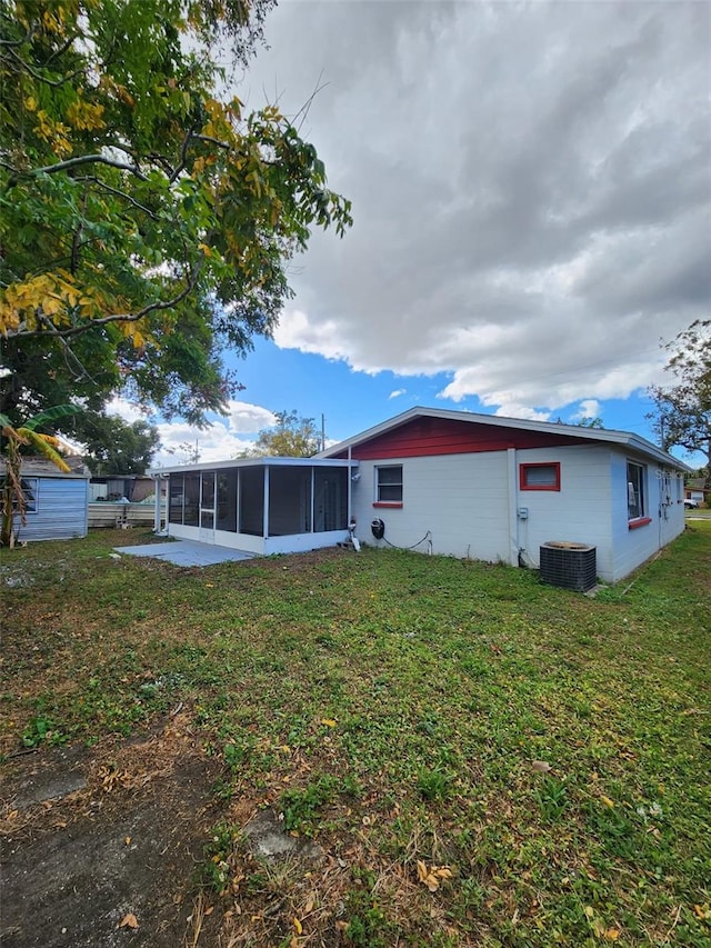 back of property featuring central AC, a sunroom, and a yard