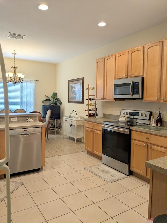 kitchen with light tile patterned floors, appliances with stainless steel finishes, decorative light fixtures, a notable chandelier, and light brown cabinetry