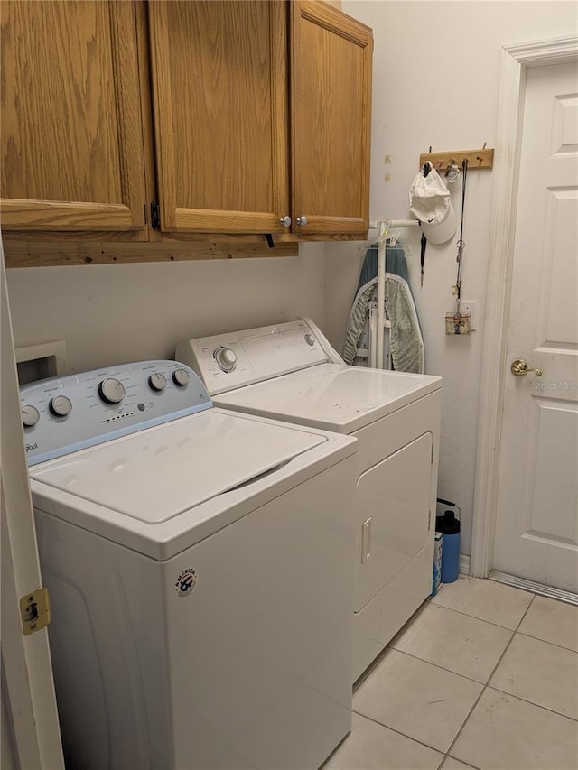 laundry room featuring cabinets, light tile patterned floors, and independent washer and dryer