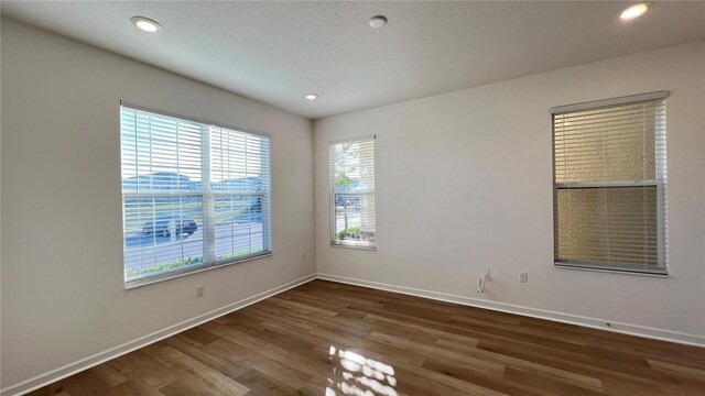 empty room with dark wood-type flooring and a textured ceiling