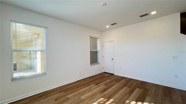 unfurnished room featuring dark hardwood / wood-style floors, a healthy amount of sunlight, and a textured ceiling