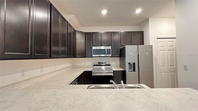 kitchen featuring dark brown cabinets, sink, light stone countertops, and stainless steel appliances