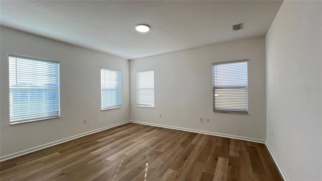 empty room with dark hardwood / wood-style floors and a textured ceiling