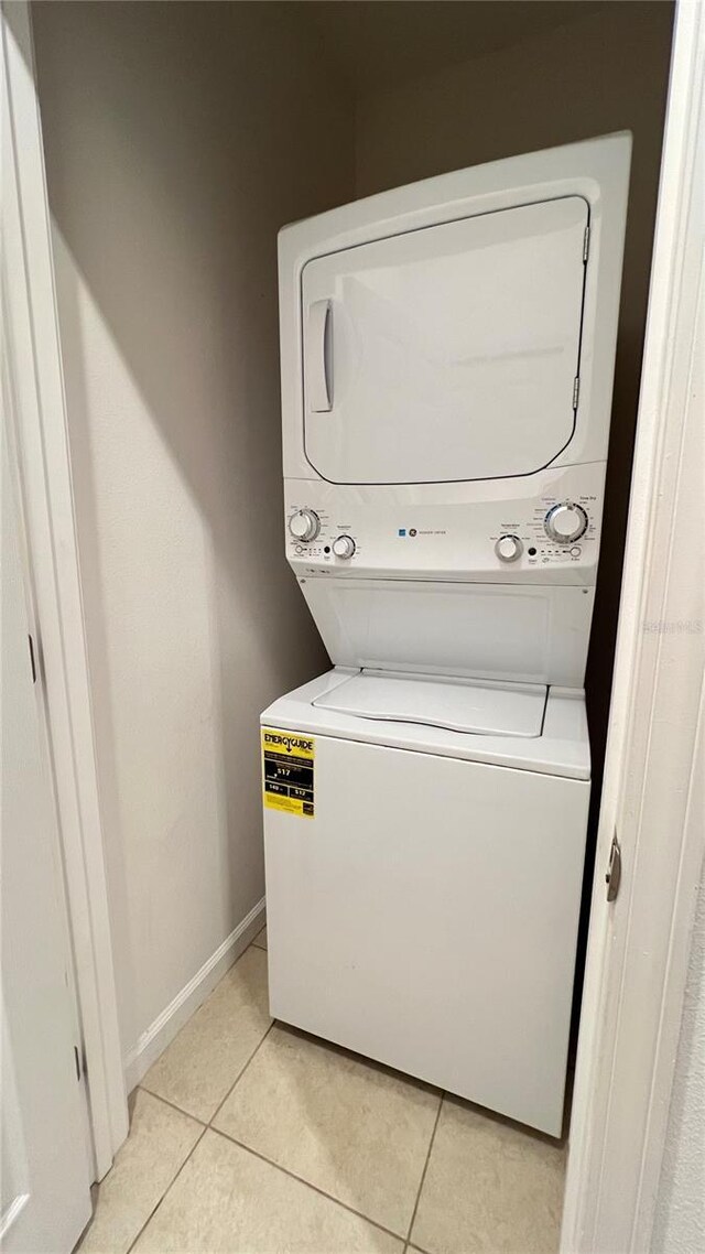 clothes washing area with stacked washer and dryer and light tile patterned floors