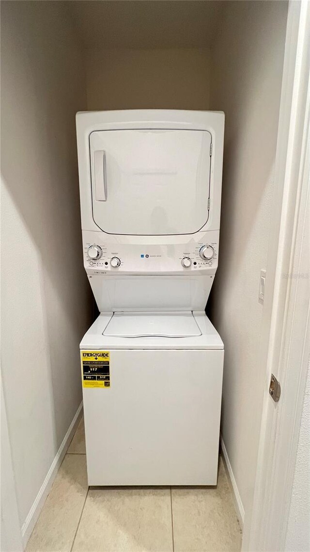 laundry area featuring light tile patterned floors and stacked washing maching and dryer