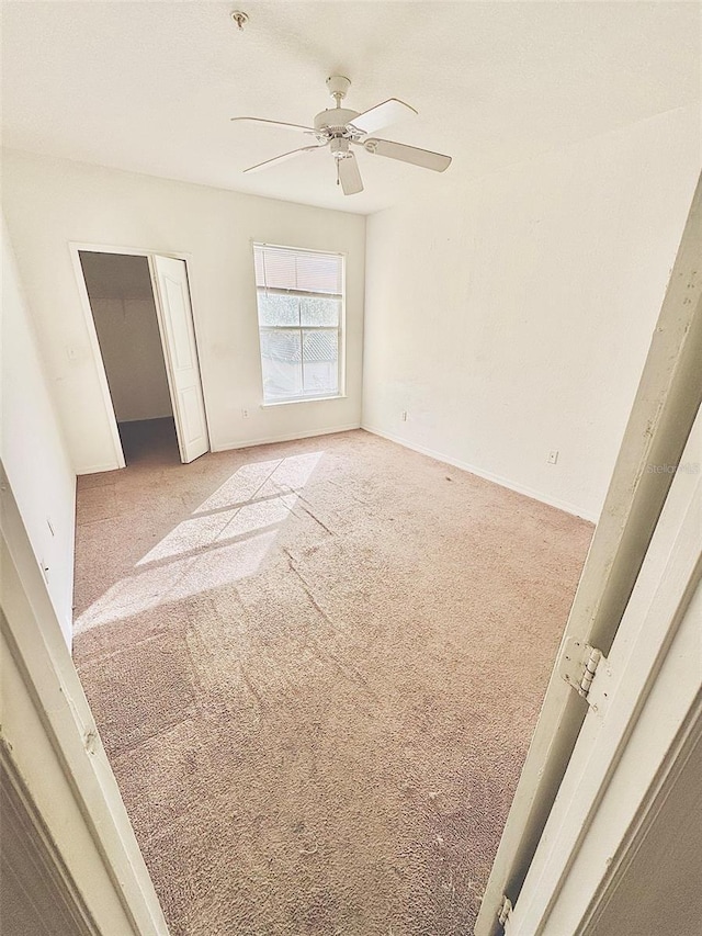 empty room featuring ceiling fan and light colored carpet