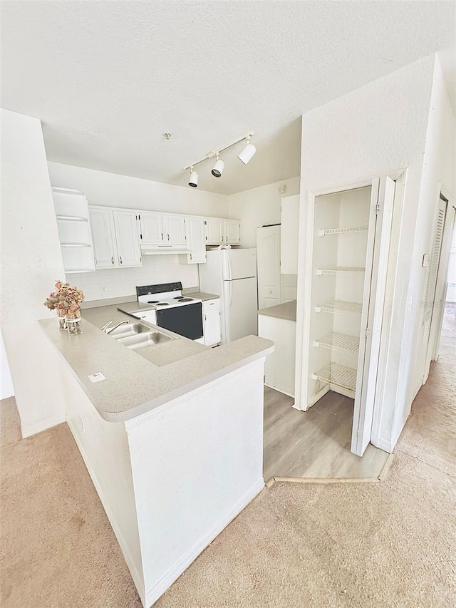 kitchen with white cabinetry, sink, kitchen peninsula, light colored carpet, and white appliances