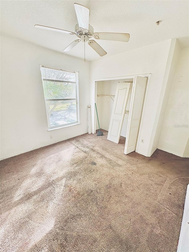 unfurnished bedroom featuring carpet, ceiling fan, a textured ceiling, and a closet