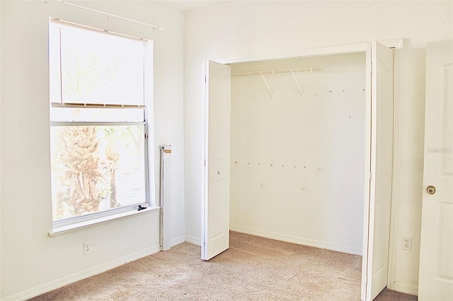 unfurnished bedroom with light colored carpet and a closet