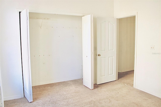 unfurnished bedroom featuring light colored carpet and a closet