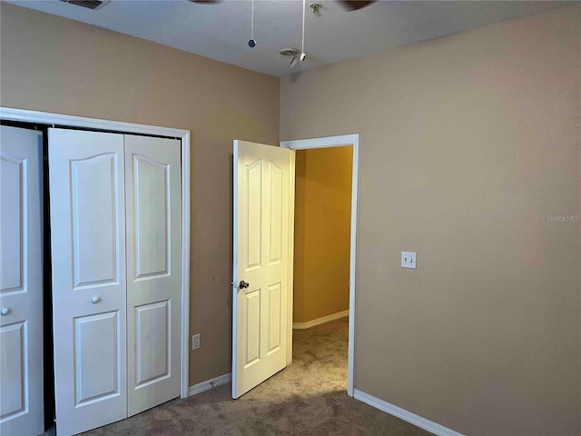 unfurnished bedroom featuring baseboards, carpet floors, a closet, and visible vents