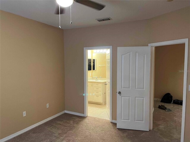 unfurnished bedroom with visible vents, light carpet, ensuite bathroom, a sink, and baseboards