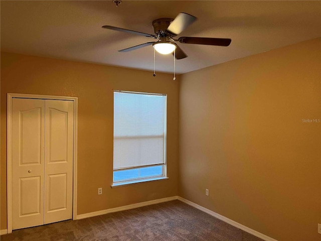 unfurnished bedroom featuring a closet, baseboards, ceiling fan, and dark carpet