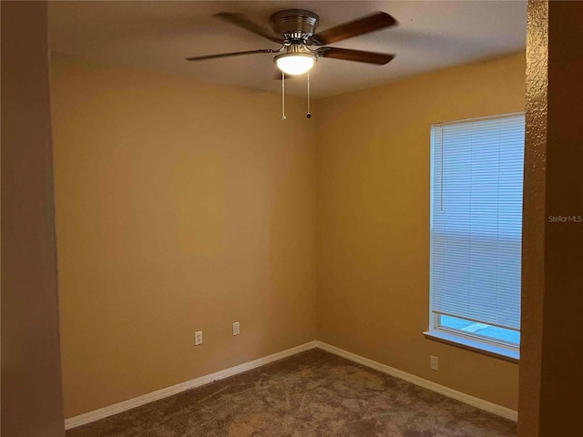 empty room featuring a ceiling fan, baseboards, and dark colored carpet