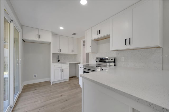 kitchen with stainless steel range with electric cooktop, sink, light hardwood / wood-style flooring, tasteful backsplash, and white cabinetry