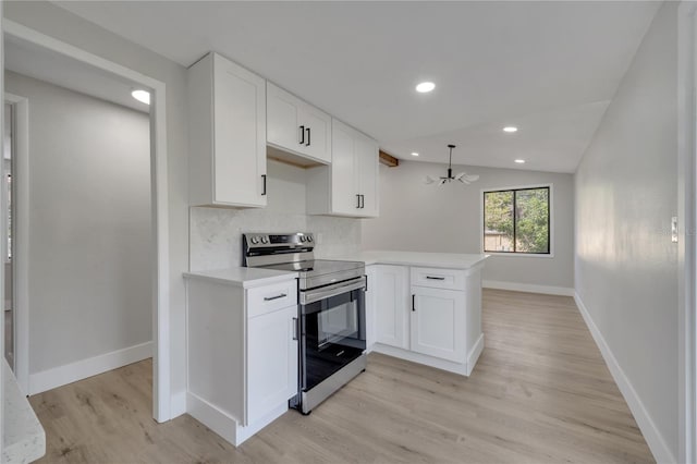 kitchen featuring kitchen peninsula, tasteful backsplash, electric stove, white cabinets, and lofted ceiling