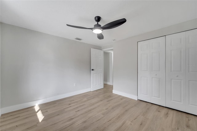 unfurnished bedroom with ceiling fan, light wood-type flooring, and a closet