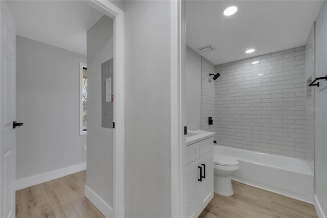 full bathroom featuring hardwood / wood-style flooring, vanity, toilet, and tiled shower / bath