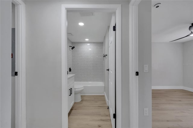 full bathroom with vanity, toilet, wood-type flooring, and tiled shower / bath combo