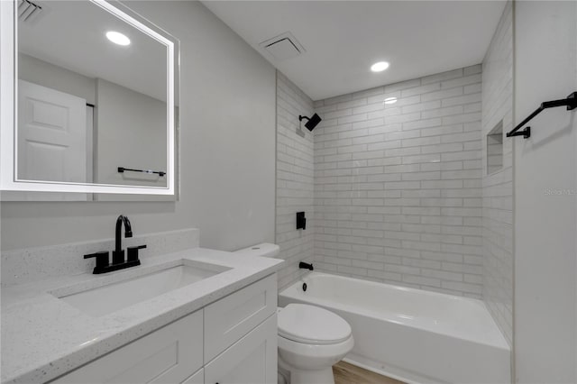 full bathroom featuring toilet, vanity, and tiled shower / bath