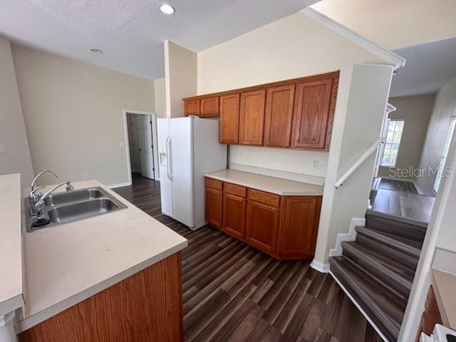 kitchen with white fridge with ice dispenser, sink, a textured ceiling, and dark hardwood / wood-style floors