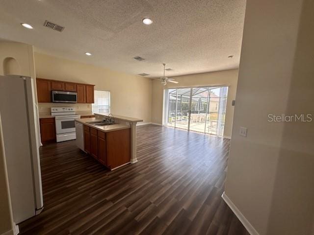 kitchen with a center island, white appliances, sink, a textured ceiling, and dark hardwood / wood-style flooring