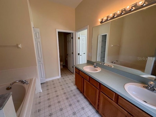 bathroom with a tub, vanity, and toilet