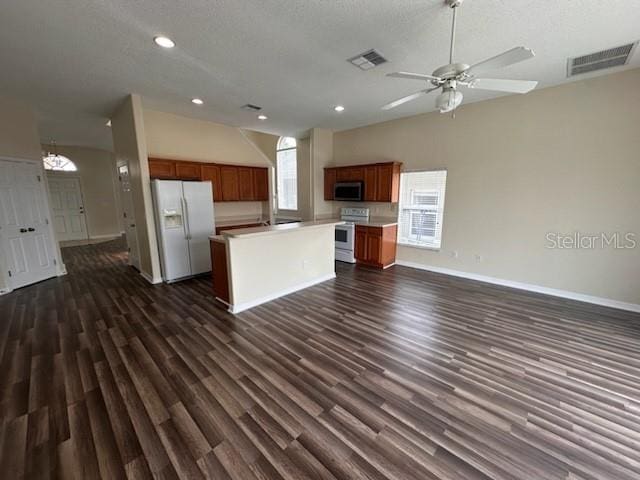 kitchen with a textured ceiling, a kitchen island, dark wood-type flooring, and white appliances