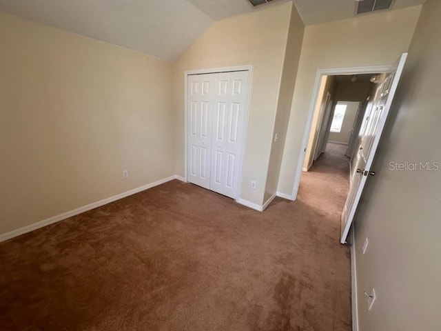 unfurnished bedroom with carpet flooring, a closet, and lofted ceiling