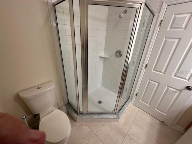 bathroom with toilet, tile patterned floors, and an enclosed shower