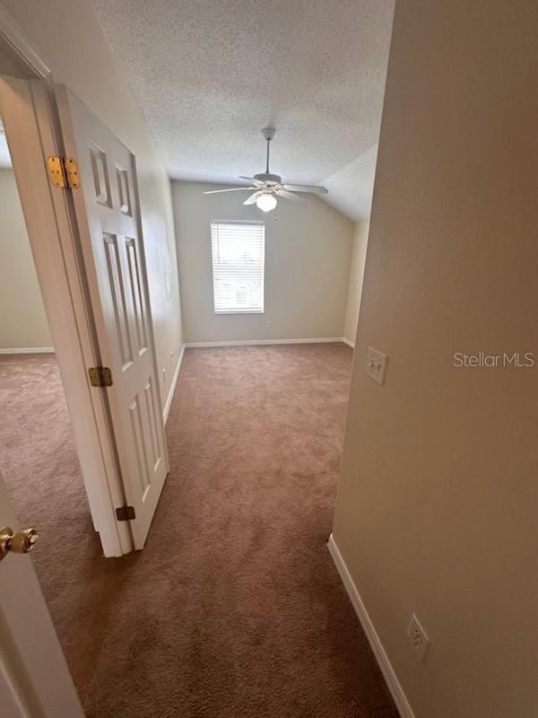 interior space featuring a textured ceiling, carpet floors, and lofted ceiling