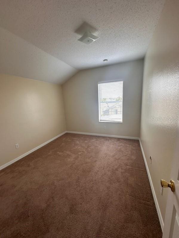 bonus room featuring a textured ceiling, dark carpet, and lofted ceiling