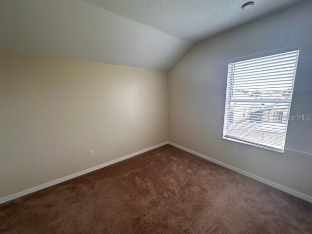 bonus room with a textured ceiling, dark carpet, and vaulted ceiling