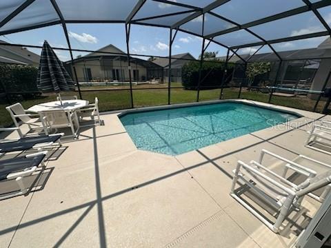 view of swimming pool featuring glass enclosure and a patio area