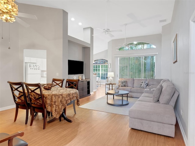 living room featuring ceiling fan, light wood-type flooring, and high vaulted ceiling