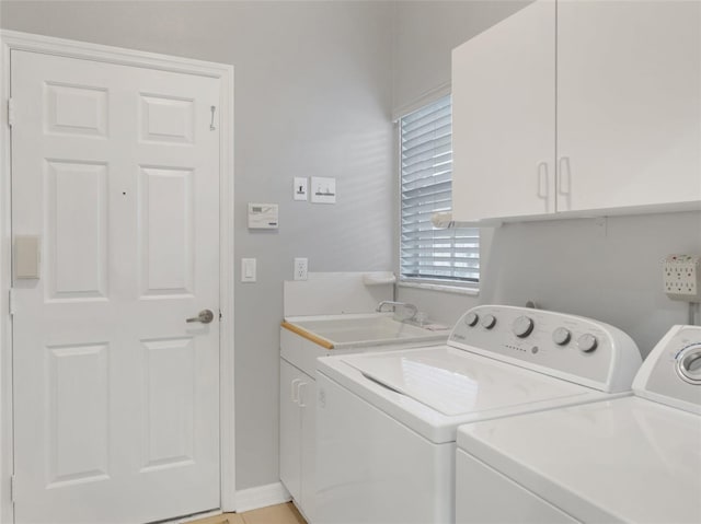 laundry area featuring cabinets, washer and clothes dryer, and sink