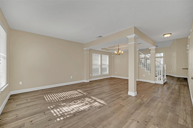 unfurnished living room featuring a wealth of natural light, light hardwood / wood-style flooring, and a notable chandelier