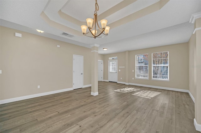 interior space featuring hardwood / wood-style floors, a textured ceiling, a tray ceiling, and a notable chandelier