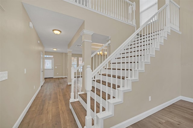 stairway featuring decorative columns and hardwood / wood-style floors